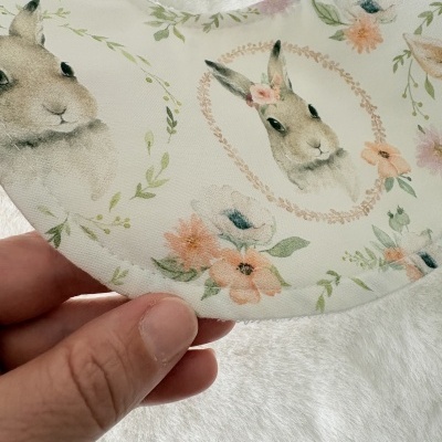 Babete com padrão de coelhos e flores em tons pastel