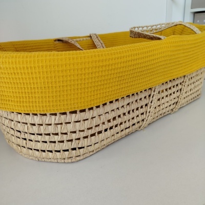 Cesto de vime com tecido amarelo na borda sobre superfície branca