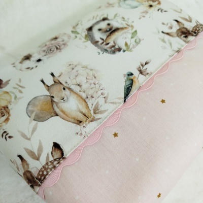 Tecido com padrão infantil de animais em cores suaves e detalhes em rosa e dourado.