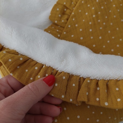 Tecido branco felpudo e amarelo com bolinhas e pregas, mãos segurando