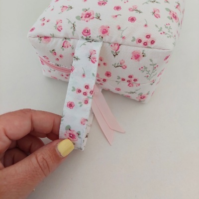Estojo quadrado de tecido branco com padrão de flores cor-de-rosa e fecho rosa