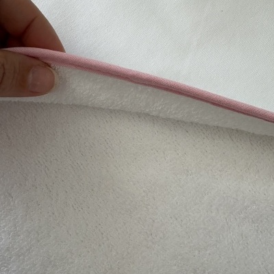 Pano branco com borda cor-de-rosa e textura macia segurado por mão