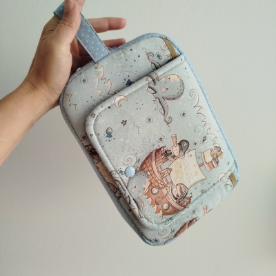 Carteira azul clara com padrão infantil e alça para pendurar.