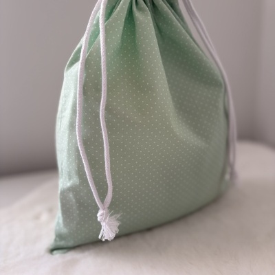 Saco de tecido verde com pontos brancos e cordão branco