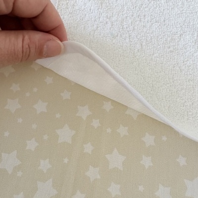toalha branca de tecido felpudo com borda lisa e superfície bege com estrelas brancas