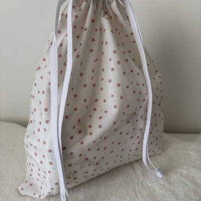 Saco de tecido branco com estrelas cor-de-rosa e cordão branco