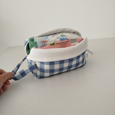 Bolsa azul e branca xadrez com fraldas e pacote rosa de papel higiénico húmido para crianças