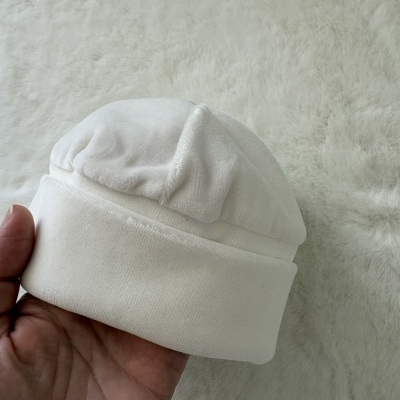 Gorro branco de tecido aveludado sendo segurado na mão