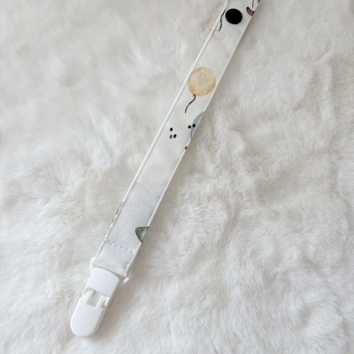 Correia de tecido com padrão de balões e fecho branco sobre fundo branco peludo
