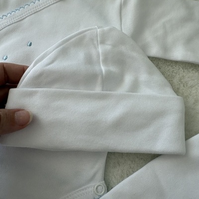 Conjunto de roupa de bebé branco com detalhes em azul e etiqueta com desenho de gato