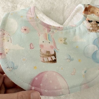 Babete para bebé com padrão de unicórnios e balões em tons pastel
