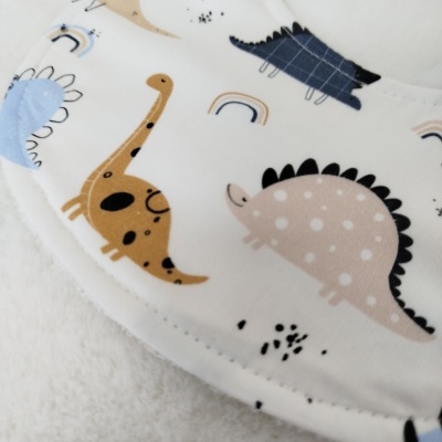 Babete branco com padrão de dinossauros coloridos