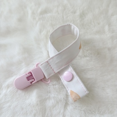 Clipe de tecido branco com botão rosa e fecho de plástico rosa sobre fundo branco peludo