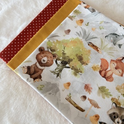 Tecidos coloridos com padrões variados de animais e pontos brancos sobre superfície branca.