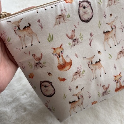 Necessaire bege com padrão de animais da floresta e elementos naturais em tecido
