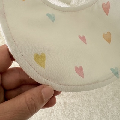 Babete branco com padrão de corações coloridos