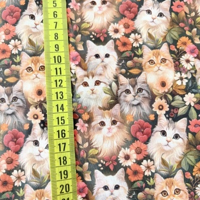 Tecido com padrão de gatos e flores com fita métrica amarela.
