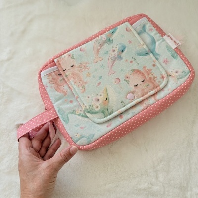 Necessaire retangular com padrão de polvos e baleias coloridas e bordos rosa com bolinhas brancas.