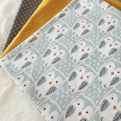 Três tecidos com padrões distintos empilhados sobre tecido branco macio