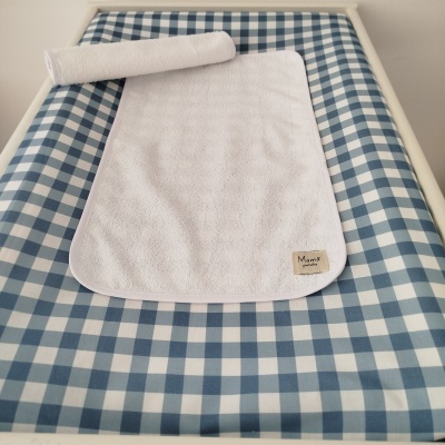 Tapete branco felpudo com etiqueta Mamã pintinha sobre superfície quadrados azul e branco