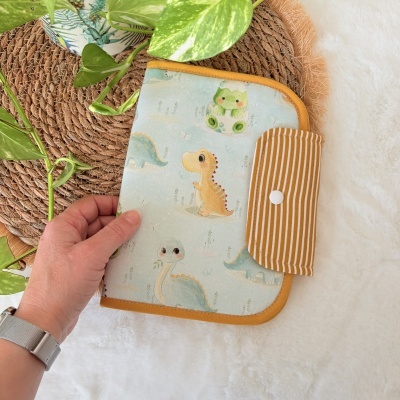 Organizador tecido azul com dinossauros e fecho riscado amarelo e branco