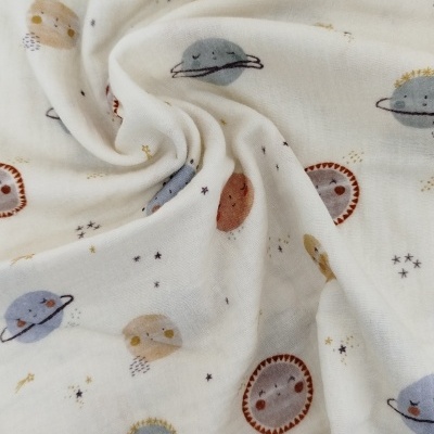 Tecido branco com padrão de planetas sorridentes em cores suaves.