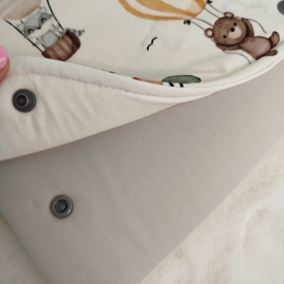 Têxtil com padrão infantil, botões de pressão e fundo cinza claro