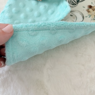 Toalha ou manta felpuda azul claro com fecho estampado e botão azul