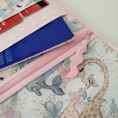 Organizador de carteira rosa com padrão de girafas e flores e compartimentos com documentos