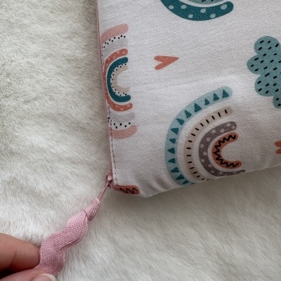 Bolsa de tecido com padrão colorido e fecho cor-de-rosa sobre superfície branca peluda