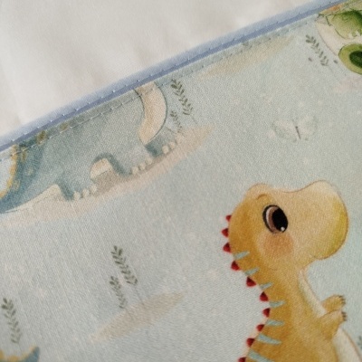 Detalhe de tecido com padrão de dinossauros e borda azul