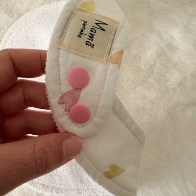 Babete de tecido branco com botões cor-de-rosa e etiqueta Mama pintinha