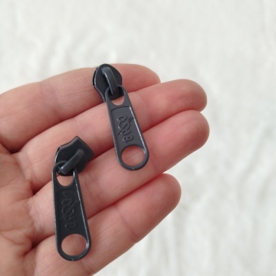 Duas pegas de fecho éclair pretas em mão com fundo branco