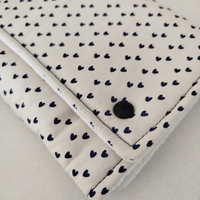 Manta branca com pequenos corações pretos e botão preto