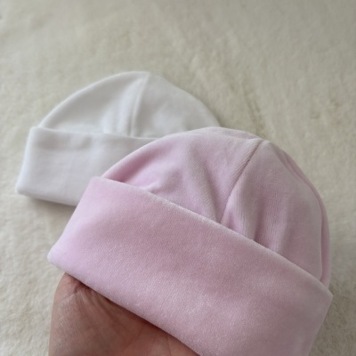 Gorros de bebé rosa e branco em superfície macia