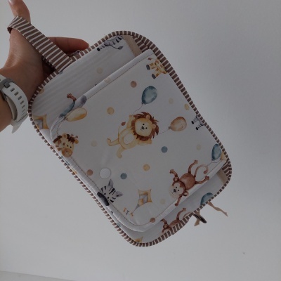 Bolsa infantil com padrão de animais e bolas coloridas, borda riscada castanha.