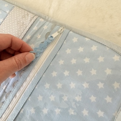 Cobertor ou almofada azul claro com estrelas brancas e fecho éclair com puxador azul ondulado