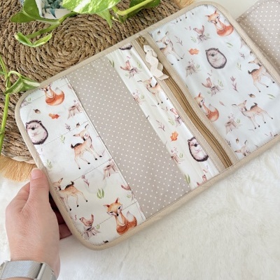 Bolsa organizadora em tecido bege com padrão de animais da floresta e fecho de correr