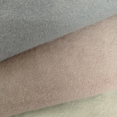 Três toalhas empilhadas em tons pastel com textura felpuda