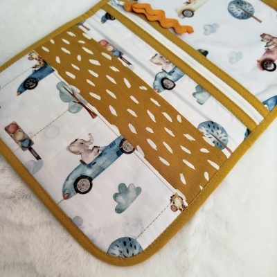 organizador tecido com estampado ursinho carros azul rosa árvores nuvens e semáforo detalhes gotas brancas fundo mostarda