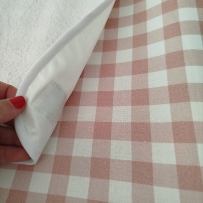 tecido xadrez branco e rosa claro com parte branca e mão segurando um canto
