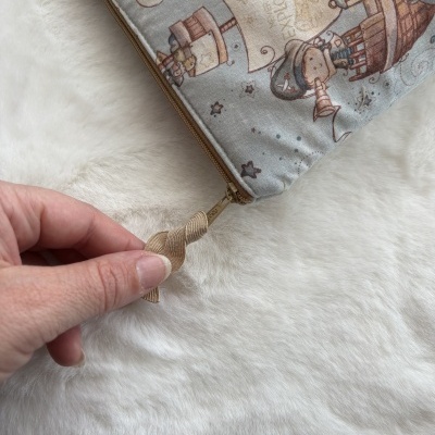 Estojo tecido cinzento com padrão de personagens em tons castanhos e azul e fecho zip bege