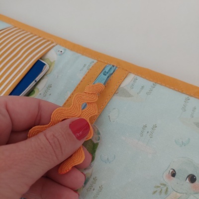 Carteira de tecido azul claro com fecho e puxador laranja, padrão com animais e folhas