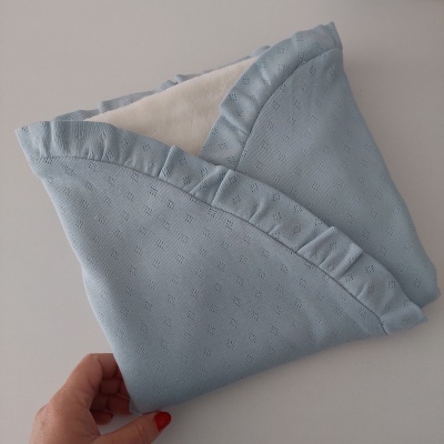 Máscara facial de tecido azul claro com padrão perfurado e forro branco felpudo
