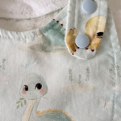 Pano de bebé com padrão de dinossauro e botões azuis claros