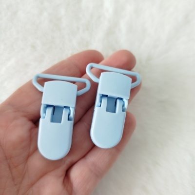 Dois clipes de plástico azuis em mão com fundo branco peludo
