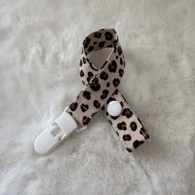 Tira com padrão animal print e fecho de plástico branco sobre superfície peluda branca