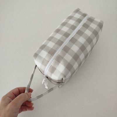 Bolsa quadrada com padrão xadrez bege e branco e fecho branco