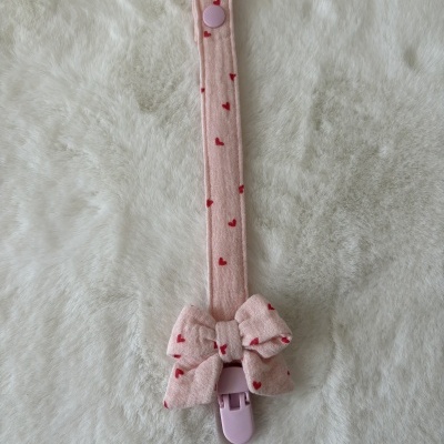 Prendedor de chupeta rosa com corações vermelhos e laço, fecho plástico rosa