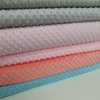 Tecidos minky em pilha com textura pontilhada em várias cores pastel